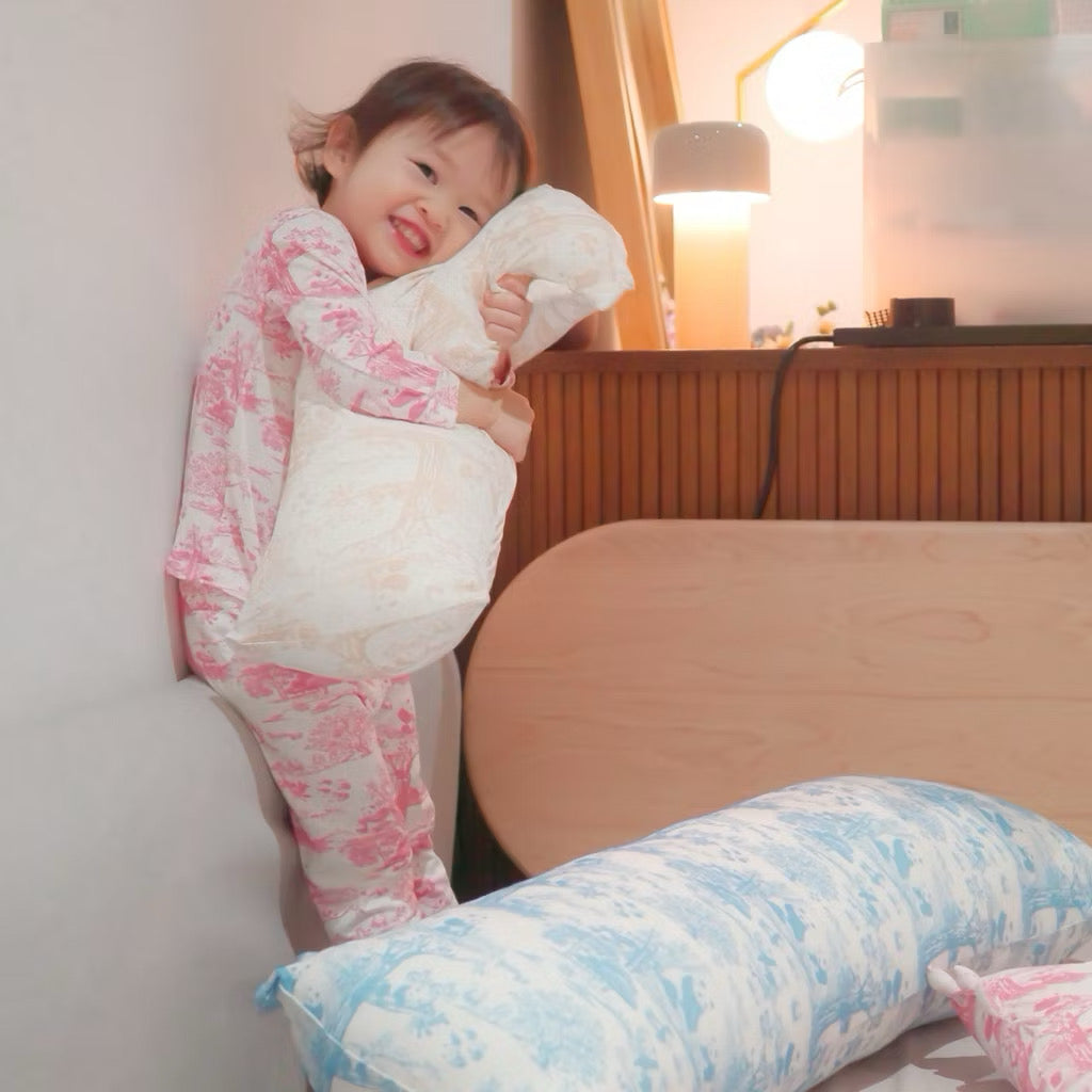 Child holding a beige-patterned bamboo kids pillow in a bedroom setting — breathable, cooling, and eczema-friendly bedding.