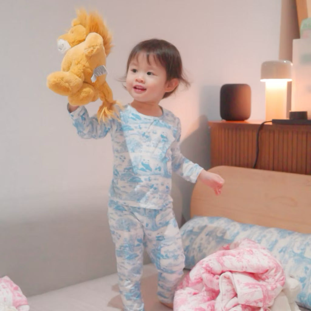 Child in bamboo pyjamas holding a yellow plush lion in a bedroom setting — soft, cooling, eczema-friendly sleepwear.