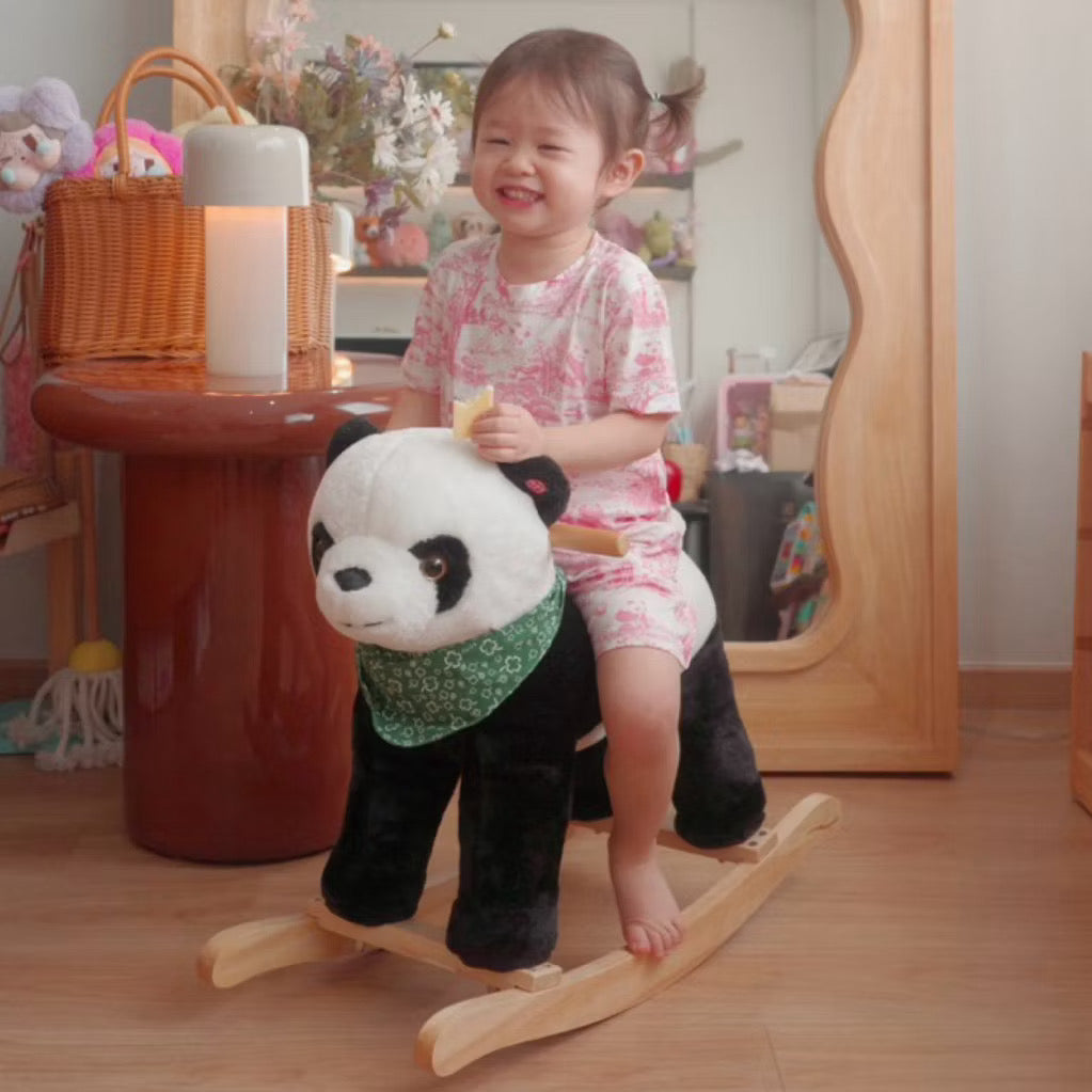 Child wearing a pink short sleeve bamboo kids pyjamas set riding a panda-shaped rocking horse in a room with wooden floor and furniture — soft, eczema-friendly sleepwear